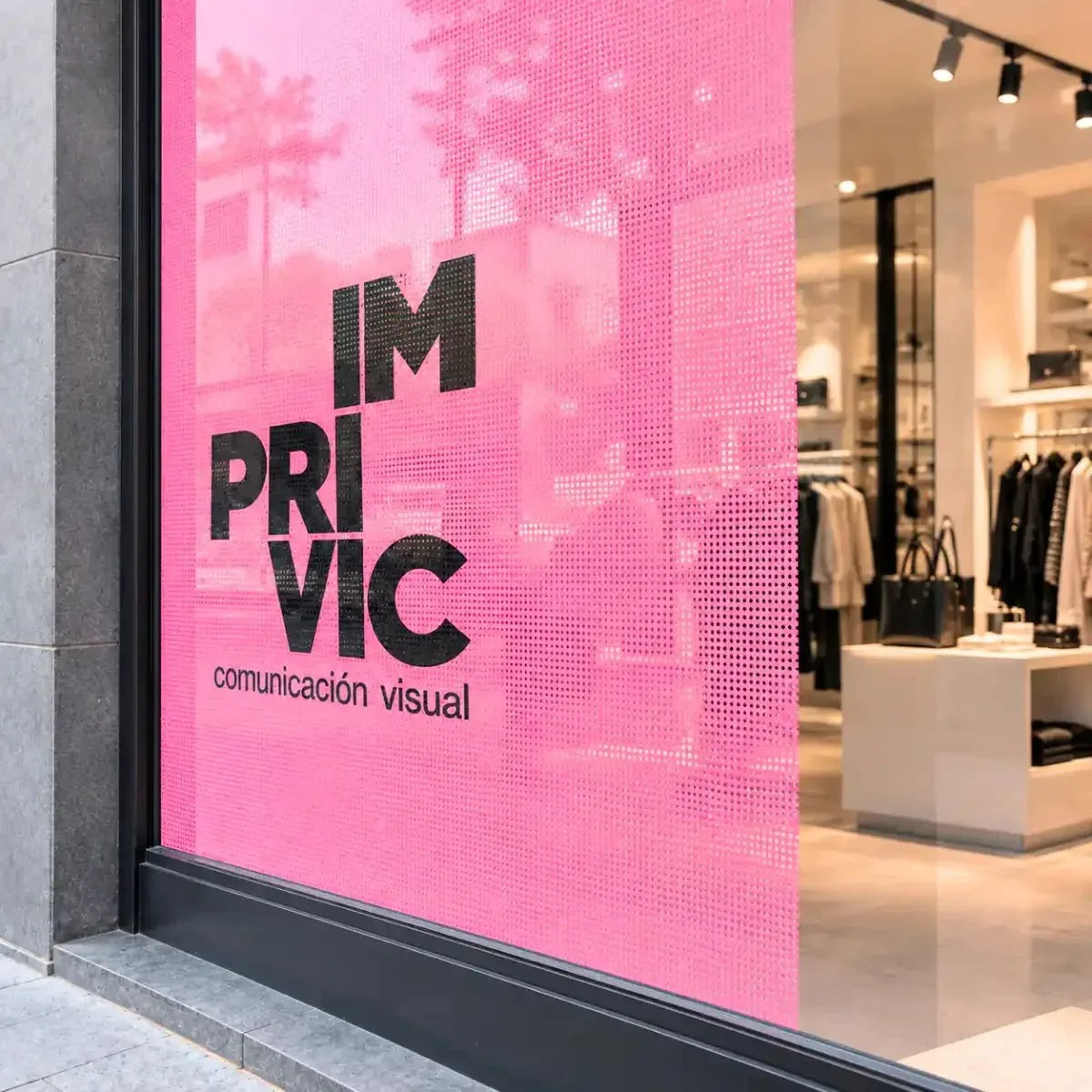 Vinilo microperforado impreso personalizado de color rosa con logotipo de Imprivic en el escaparate de una tienda de ropa